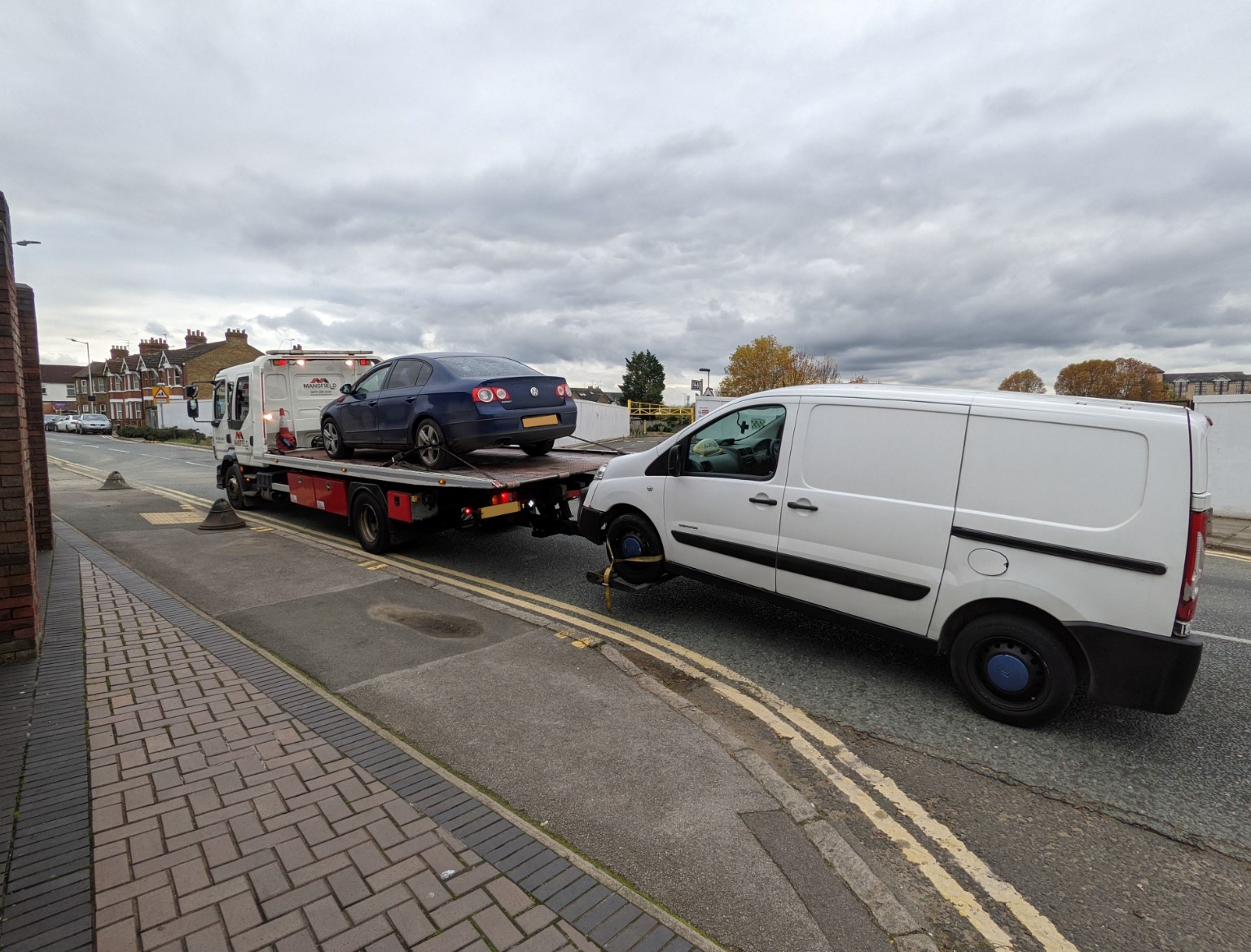 A tow truck loading on a car and a van which have been seized by police.