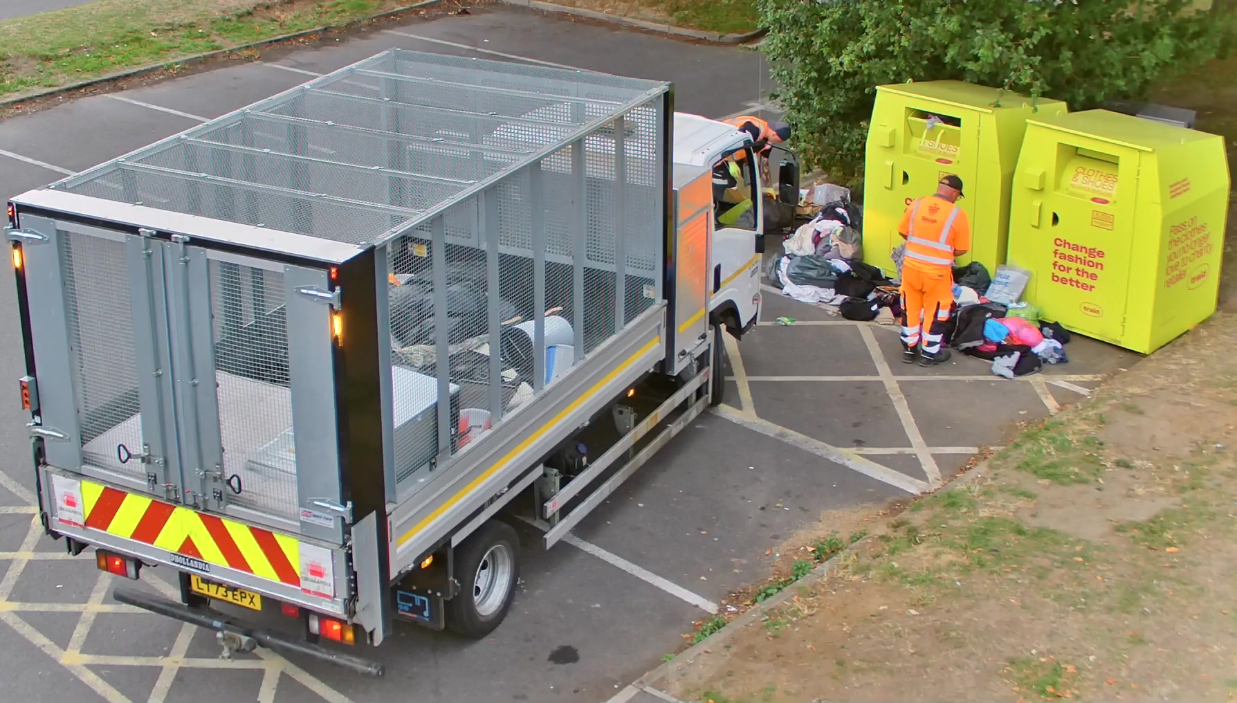 Image of council workers collecting flytipping from outside a charity clothing bank