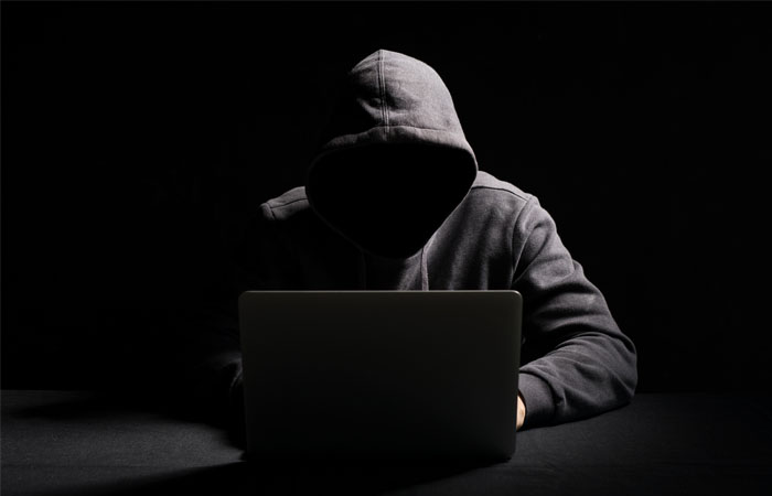 Web stalker working on laptop in the dark