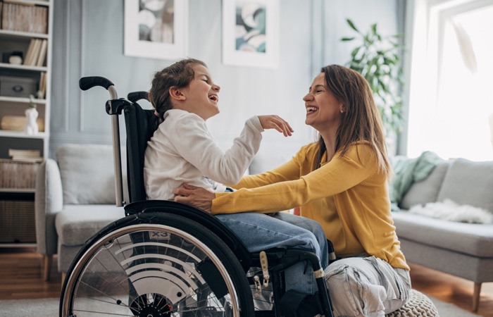 Mom and young daughter on wheelchair at home