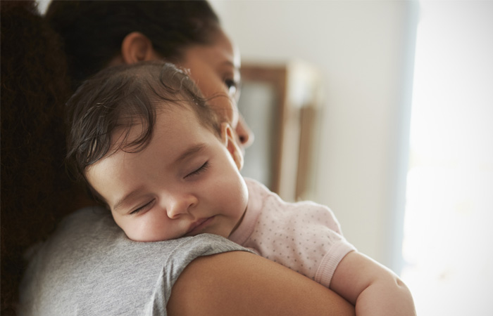 Close Up Of Mother Cuddling Sleeping Baby Daughter At Home