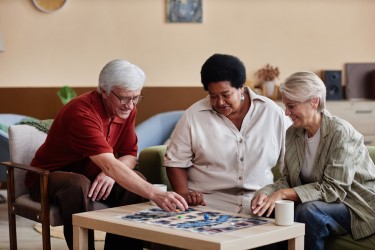 Three people around a low table playing a board game.