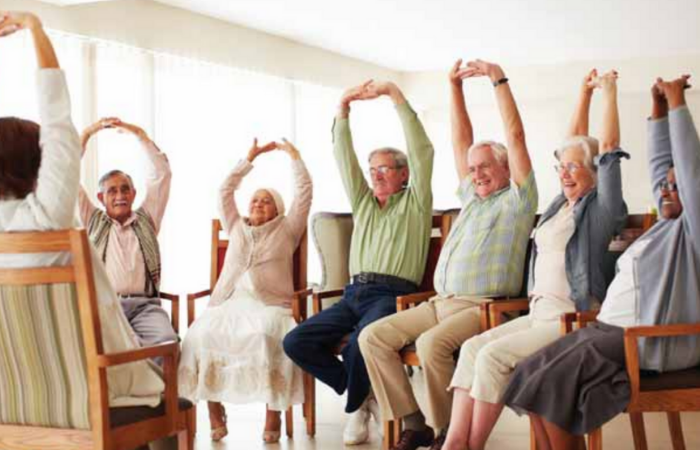 Group of older people doing exercise while seated on chairs